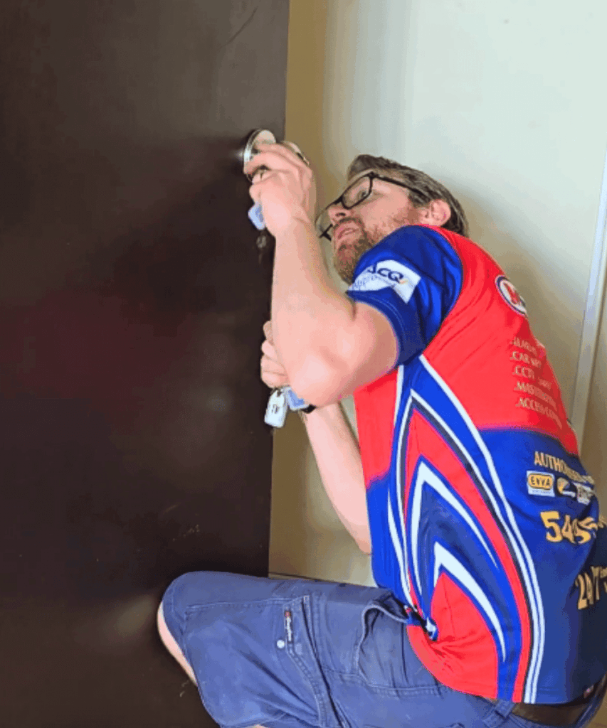 Technician rekeying a doorknob in an apartment, providing residential locksmith services in Moreton Bay