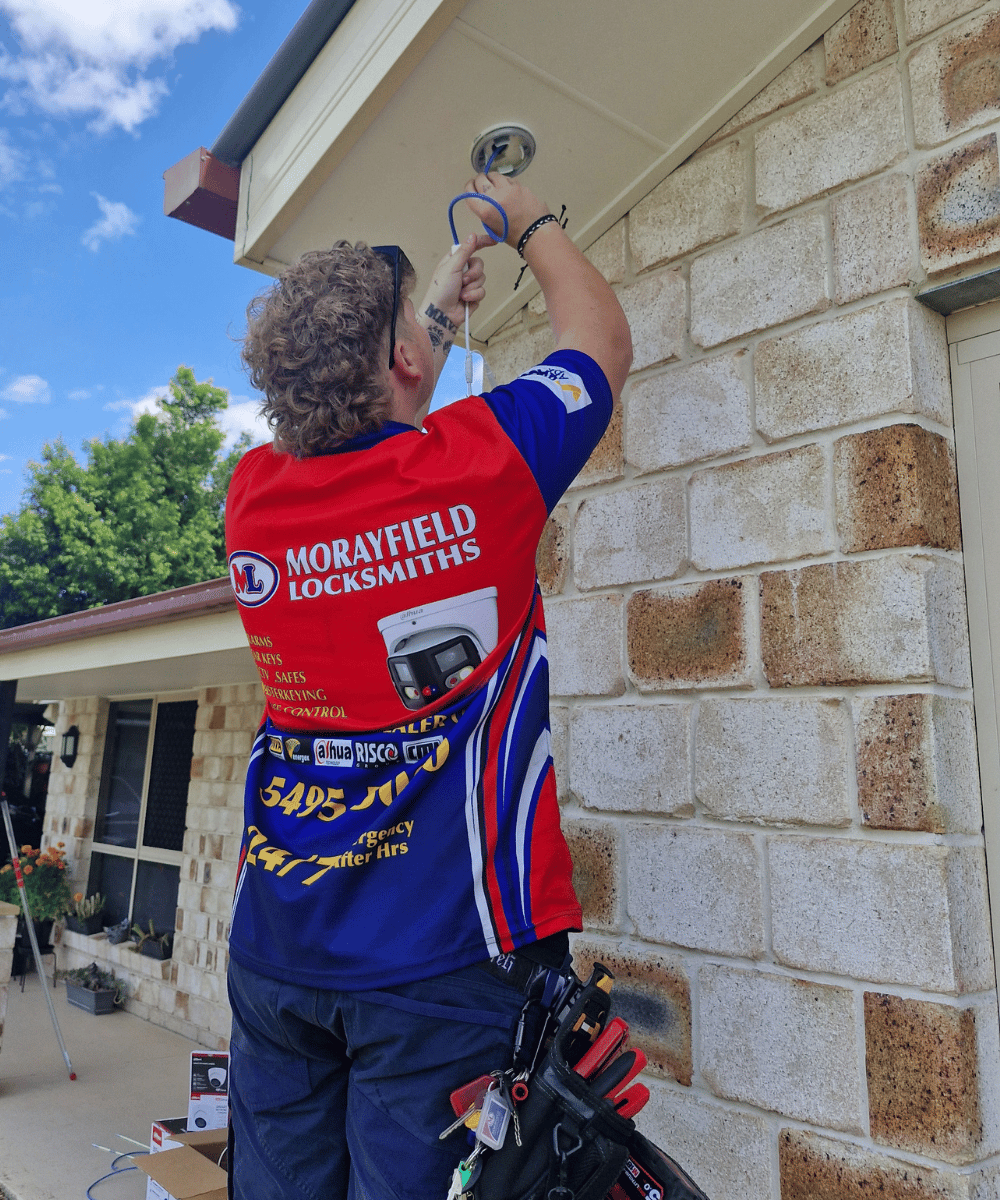 Morayfield Locksmiths technician mounting outdoor CCTV camera on a business building.