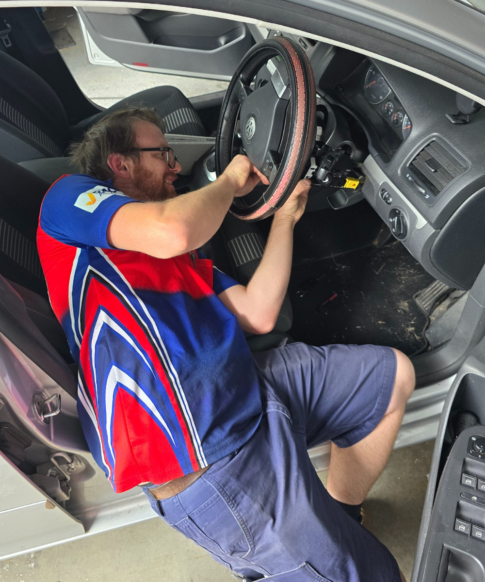 Morayfield Locksmiths technician seated in a vehicle repairing and reprogramming a faulty ignition key for a customer in the Moreton Bay region