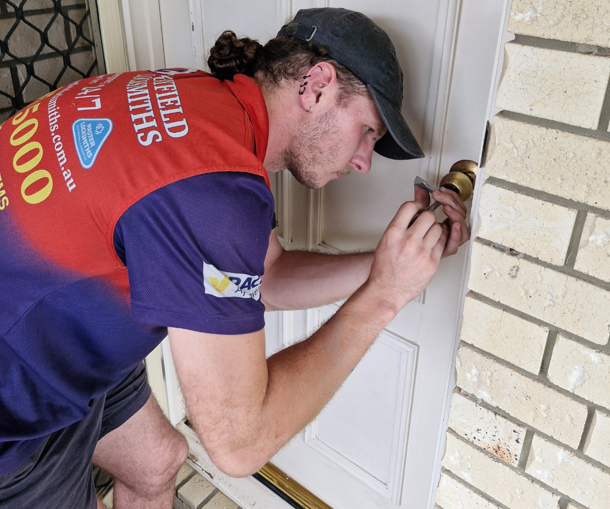A locksmith in a Morayfield Locksmiths uniform using professional tools to gain entry to a residential door lock.